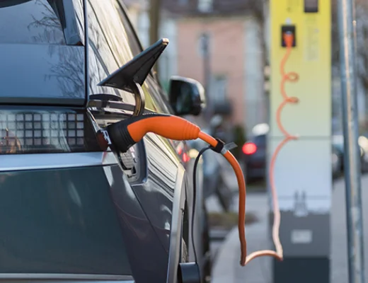 Elektroauto lädt an einer öffentlichen Ladesäule mit angeschlossenem Ladekabel