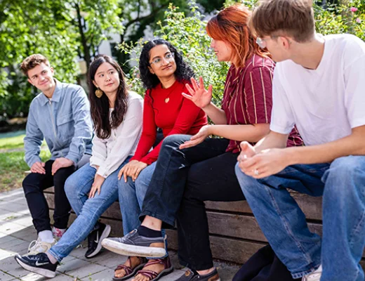 eine Gruppe von jungen Menschen sitzt draußen auf einer Bank