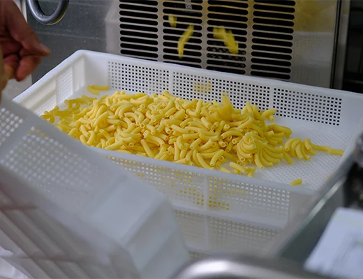 Eine Mehrweg-Box mit frischer Pasta, in die weiter Pasta reinfällt