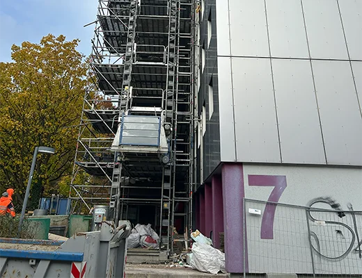 Eine Hausfassade mit einer 7. Mit einem Baugerüst vorm Haus. 