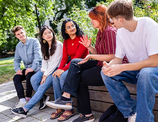 Eine Gruppe von Personen sitzen draußen auf der Bank