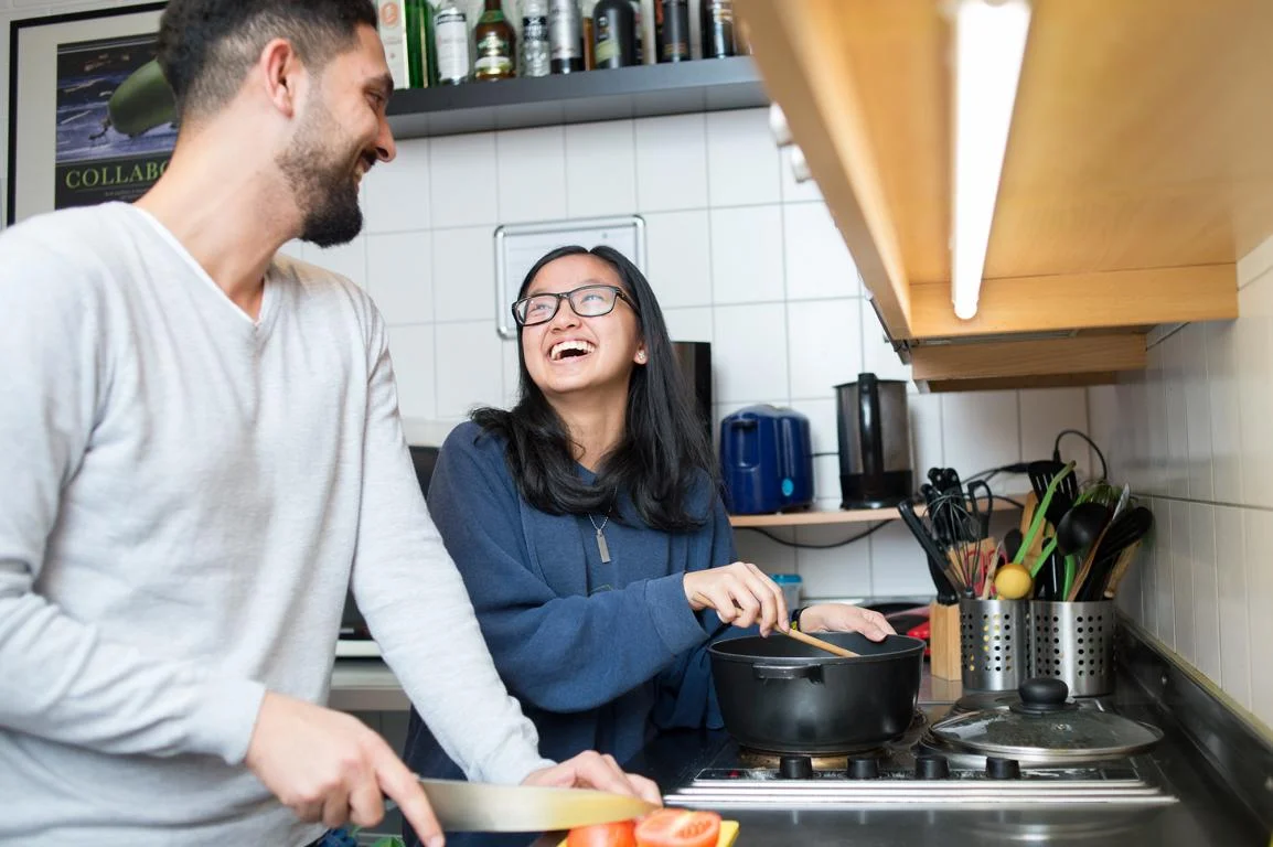 Ein junger Mann und eine junge Frau stehen gemeinsam am Herd und kochen