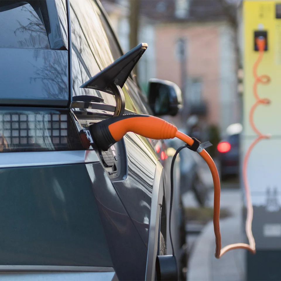 Elektroauto lädt an einer öffentlichen Ladesäule mit angeschlossenem Ladekabel 