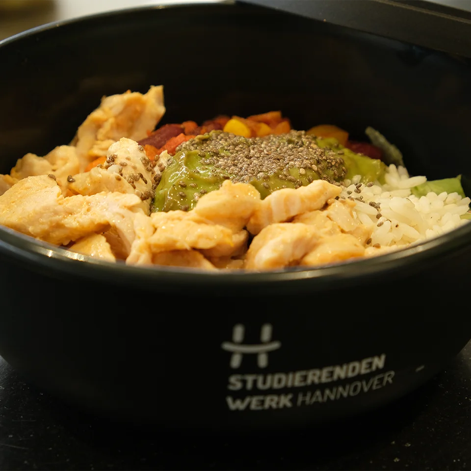 Ein Hähnchengericht in der Mehrwegschale mit Avocado-Dip