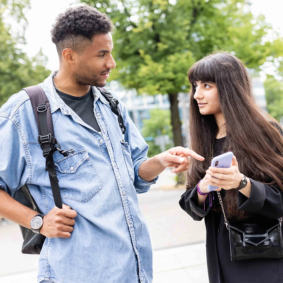 Eine junge Frau steht links im Bild und spricht mit einem jungen Mann
